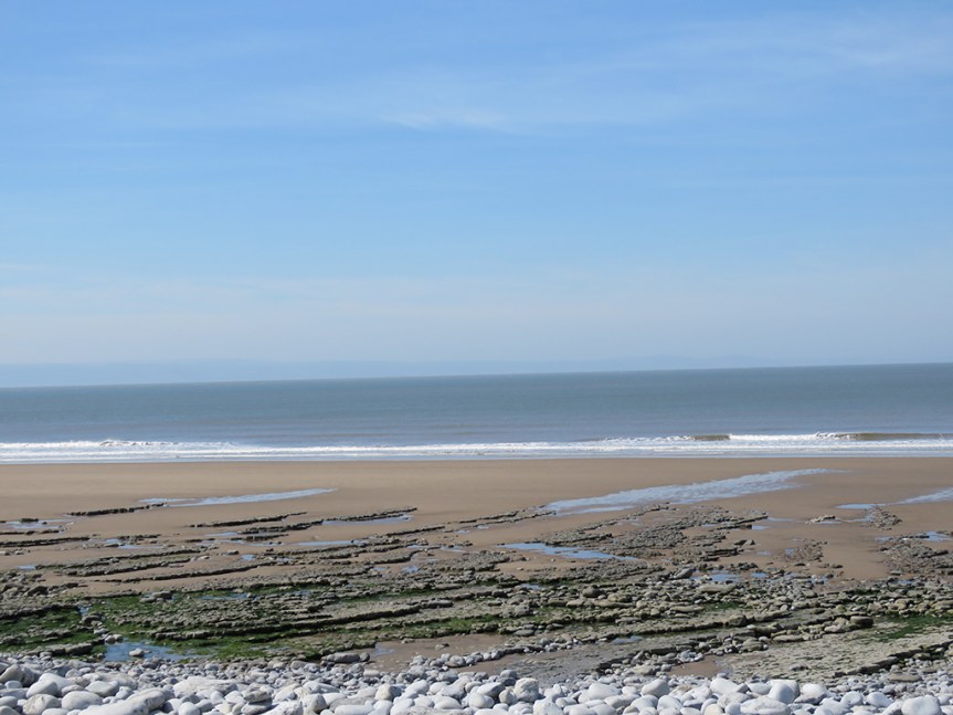 a broad rocky beach with sand toward the surf