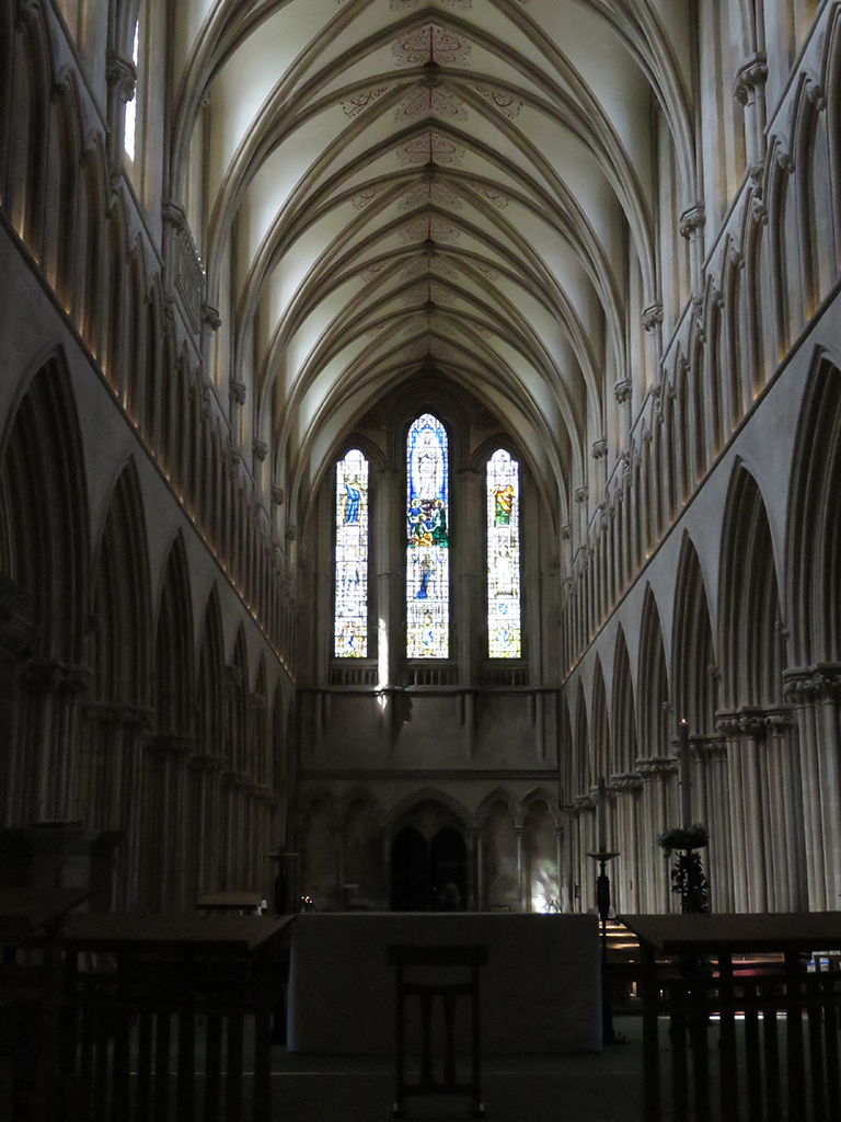 Interior view of a llarge church nave with stained-glass windows at the far end.