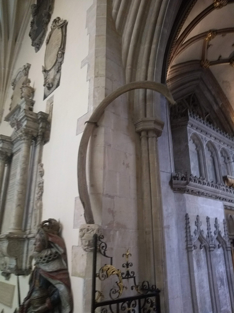 Whalebone affixed to the interior wall of a church, by a stone archway.