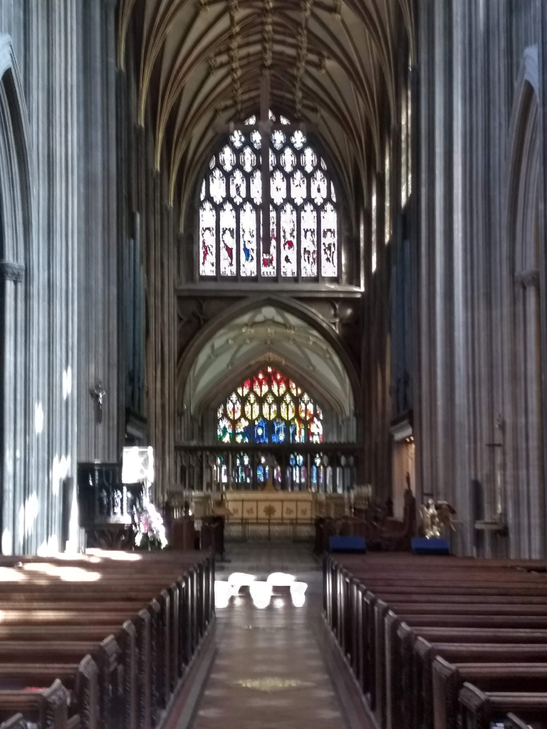 Church interior with high vaulted ceiling and stained glass windows at the far end.