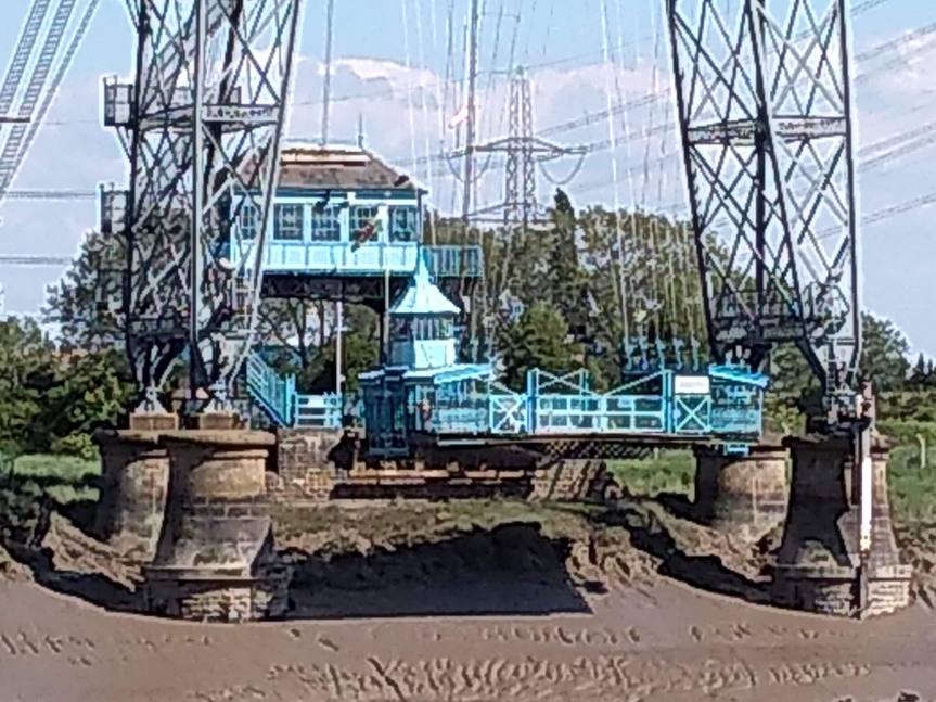 Ferry gondola hanging beneath a steel tower.